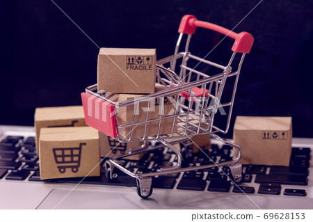 Shopping online. cardboard box with a shopping cart logo in a trolley on laptop keyboard. Shopping service on The online web. offers home delivery. Shopping online. cardboard box with a shopping cart logo in a trolley on laptop keyboard. Shopping service on The online web. offers home delivery. 69628153