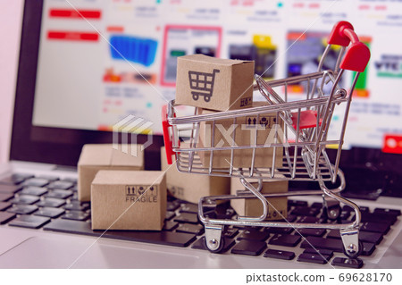 Shopping online. cardboard box with a shopping cart logo in a trolley on laptop keyboard. Shopping service on The online web. offers home delivery. Shopping online. cardboard box with a shopping cart logo in a trolley on laptop keyboard. Shopping service on The online web. offers home delivery. 69628170