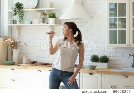 Carefree young female singing in the kitchen 69628295