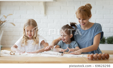 Charming kids and mommy preparing dough for cookies Charming kids and mommy preparing dough for cookies 69628298