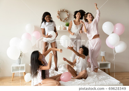 Young beautiful mixed race female friends playing with balloons. 69628349