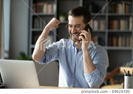 Excited young man triumph receive good news online 69628390