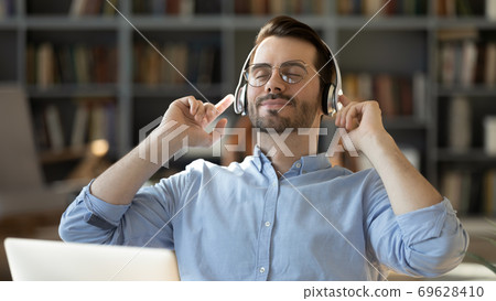 Happy millennial man enjoy good quality sound in headphones Happy millennial man enjoy good quality sound in headphones 69628410