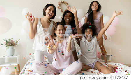 Happy young multiracial girlfriends in nightwear posing for funny photo. Happy young multiracial girlfriends in nightwear posing for funny photo. 69628487