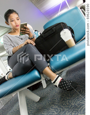 A young woman with mobile phone sitting in waiting room. Traveler waits for his transport connection A young woman with mobile phone sitting in waiting room. Traveler waits for his transport connection 69628590