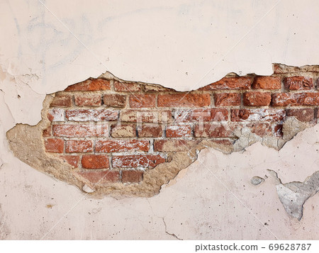Damaged light pink wall. Old cracked concrete cement wall. Brick wall with damage. Damaged light pink wall. Old cracked concrete cement wall. Brick wall with damage. 69628787