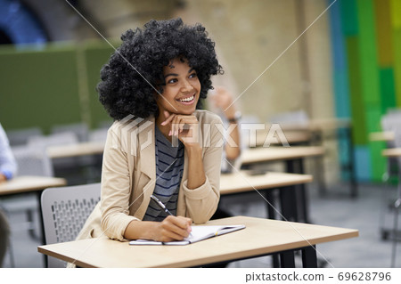 Happy mixed race businesswoman sitting at desk in the modern coworking space, listening to coach and smiling during corporate business training 69628796