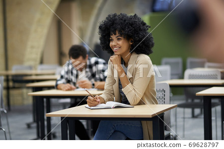 New skills. Happy mixed race businesswoman sitting at desk in the modern coworking space, listening to coach and smiling during corporate business training 69628797