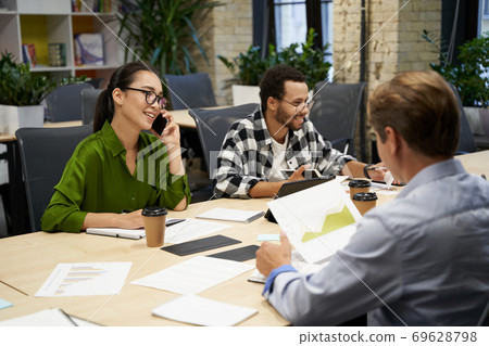 Young successful multiracial business team sitting at the desk and working together in the modern office Young successful multiracial business team sitting at the desk and working together in the modern office 69628798