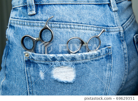 professional hairdressing scissors lie in the pocket of jeans. professional hairdressing scissors lie in the pocket of jeans. 69629351