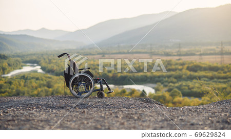 Empty wheelchair on the mountains at sunset. Concept of travel of people with disabilities. 69629824