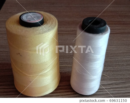 golden and white color yarn on wooden table 69631150