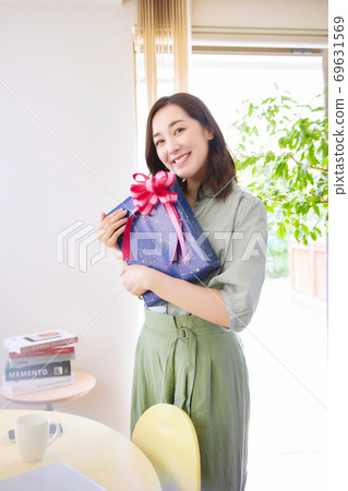 A smiling woman holding a gift box 69631569