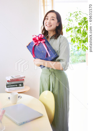 A smiling woman holding a gift box 69631570