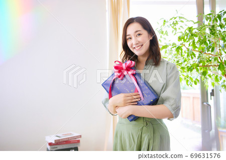 A smiling woman holding a gift box A smiling woman holding a gift box 69631576