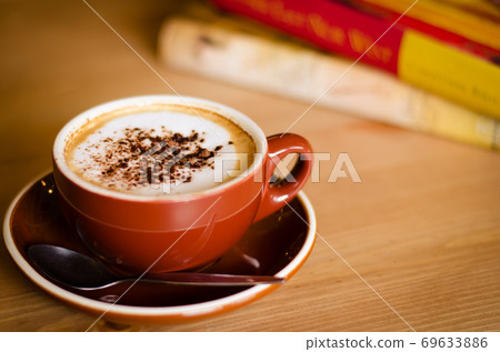 Cup of Cappuccino Coffee and Books in Cozy Cafe. Cup of Cappuccino Coffee and Books in Cozy Cafe. 69633886