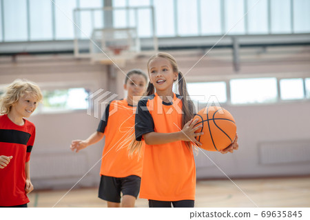 Kids in bright sportswear having basketball game Kids in bright sportswear having basketball game 69635845