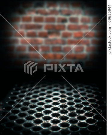 metal perforated table surface in a dark basement against a brick wall close up 69636944