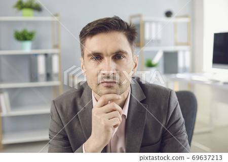 Business man looking at camera during videocall in office Business man looking at camera during videocall in office 69637213