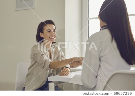 Smiling woman patient shaking hand to doctor after successful consultation in medical clinic Smiling woman patient shaking hand to doctor after successful consultation in medical clinic 69637259