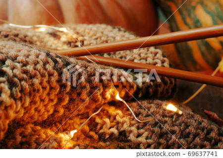 Composition with yarn, wooden needles and colorful pumpkins. 69637741