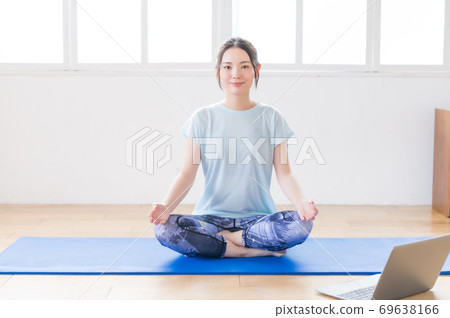 Young woman doing yoga online in the living room Young woman doing yoga online in the living room 69638166