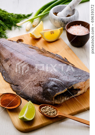 Raw fresh halibut on wooden cutting board Raw fresh halibut on wooden cutting board 69639372