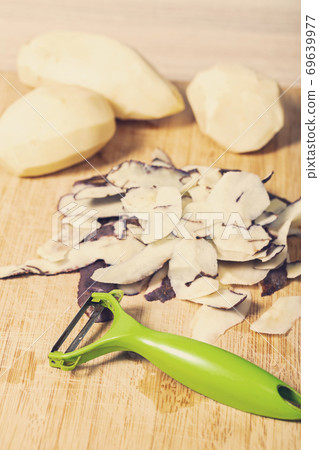 peeling potatoes on a wooden table peeling potatoes on a wooden table 69639977