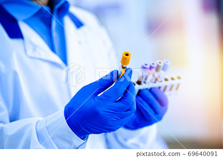 Hands in rubber gloves hold test tubes. Hands in rubber gloves hold test tubes. 69640091