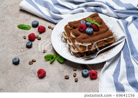 portion of Classic tiramisu dessert with raspberries and blueberries on grey concrete background portion of Classic tiramisu dessert with raspberries and blueberries on grey concrete background 69641156