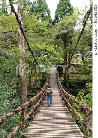 A person crossing a suspension bridge A person crossing a suspension bridge 69642802