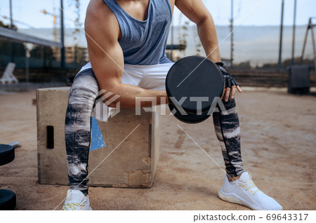 Man doing exercise with dumbbell, street workout Man doing exercise with dumbbell, street workout 69643317