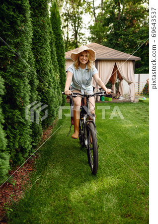 Female gardener poses on bicycle in the garden 69643537