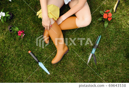 Female gardener sitting on the grass in the garden 69643538
