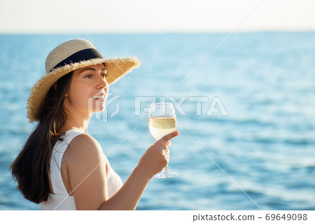 woman holding glass of wine by the sea 69649098
