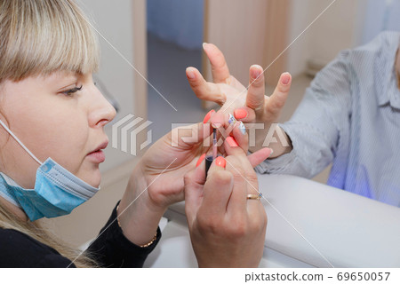 Manicuring nails - application of base coat. Selective focus, high key 69650057