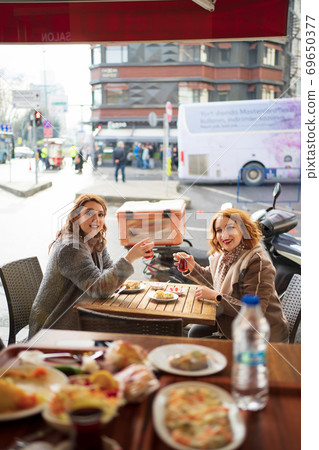 Two girlfriends sitting in a cafe and drink tea Two girlfriends sitting in a cafe and drink tea 69650377