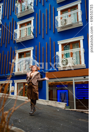 red-haired girl brown clothes blue wall umbrella 69650785
