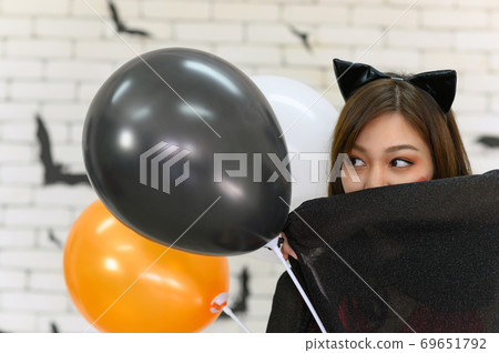 Portrait of beautiful young asian woman wearing witch costume posing with balloons on background decorated for party concept - Free space for copy text Portrait of beautiful young asian woman wearing witch costume posing with balloons on background decorated for party concept - Free space for copy text 69651792