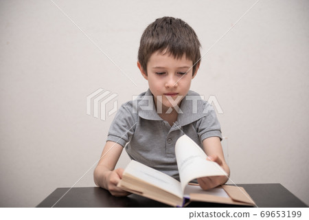 A schoolboy without expressed interest reads a book 69653199