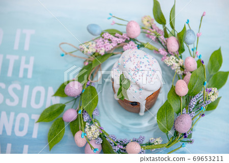 Easter cake in the center of a wreath of spring flowers on a blue vintage background with text and copy space Easter cake in the center of a wreath of spring flowers on a blue vintage background with text and copy space 69653211