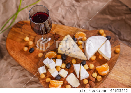 glass of wine and Assorted cheeses on wooden Board 69653362