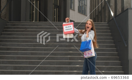 Girl showing Black Friday inscription on shopping bags, smiling, satisfied with low prices purchases 69653368