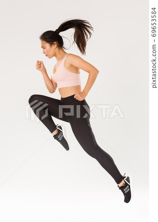 Sport, gym and healthy body concept. Full length of serious focused female runner, motion shot of girl running in air, fitness training of cute slim sportswoman, athlete workout in active wear 69653584