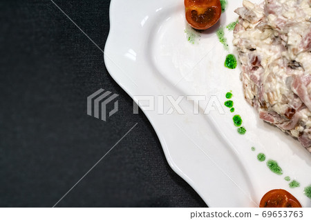 fragment of a white plate with salad on a black 69653763