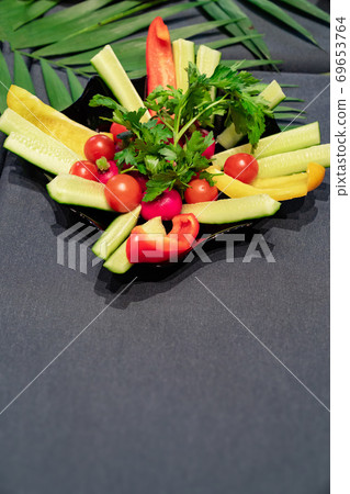 plate with sliced vegetables on a black background plate with sliced vegetables on a black background 69653764