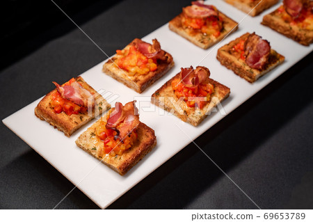 toast with vegetables and bacon, black background. 69653789