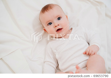 baby in white clothes lying on his back on the bed baby in white clothes lying on his back on the bed 69653790