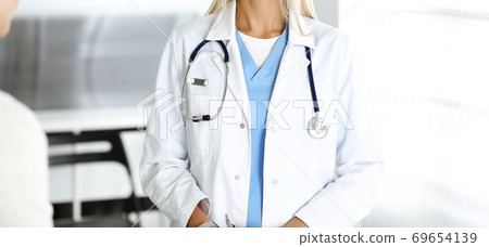 Unknown woman-doctor communicating with female patient. Physician checks medical history record and exam results, close-up. Medicine concept 69654139