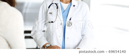Unknown woman-doctor and patient in hospital. Blonde physician controls medication history records and exam results while using clipboard, close-up. Medicine concept Unknown woman-doctor and patient in hospital. Blonde physician controls medication history records and exam results while using clipboard, close-up. Medicine concept 69654140